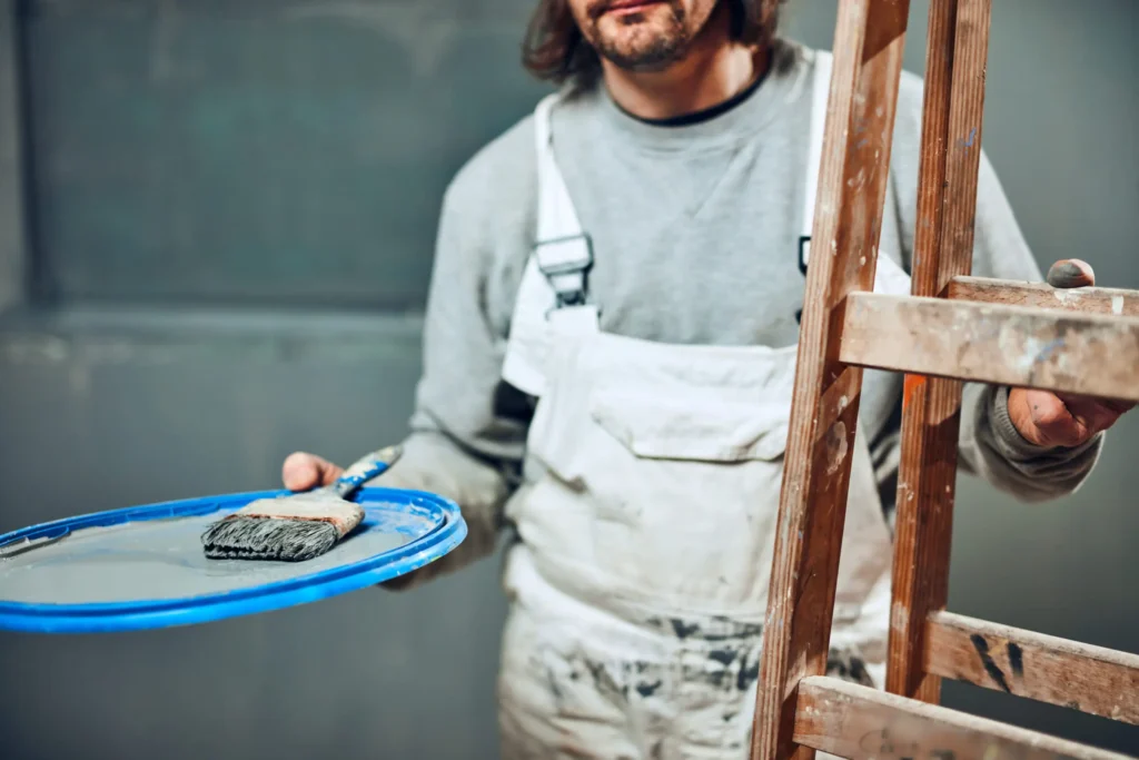 Two smiling construction workers hold a tool,