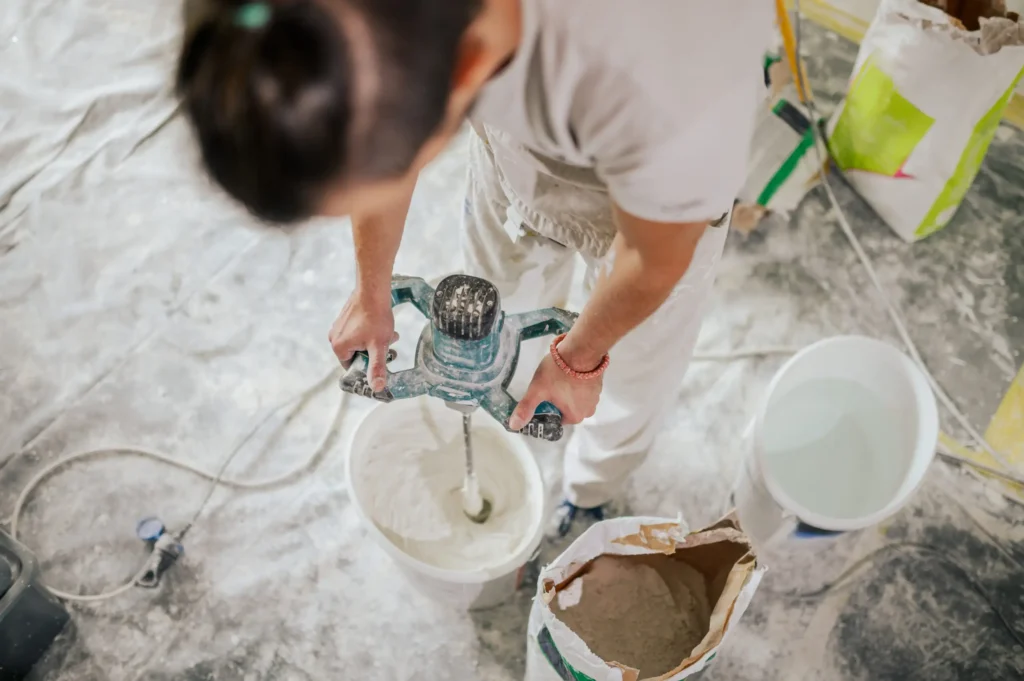 man stands holding a hard hat and various tools